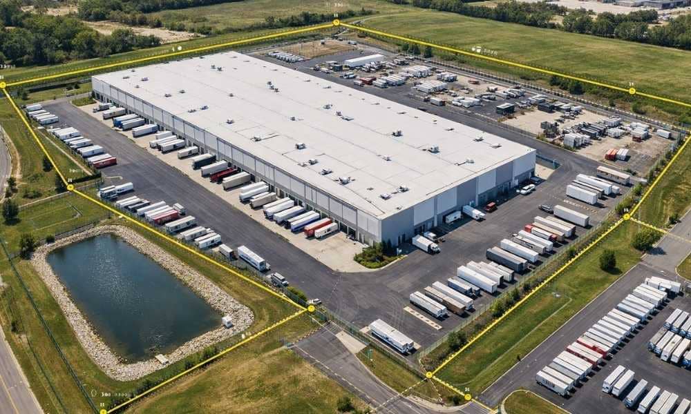 Alta survey warehouse property | ALTA Land Survey Aerial view of a warehouse distribution center with property boundary lines, truck courts, loading docks, outdoor storage, and a stormwater detention pond shown as part of an ALTA survey