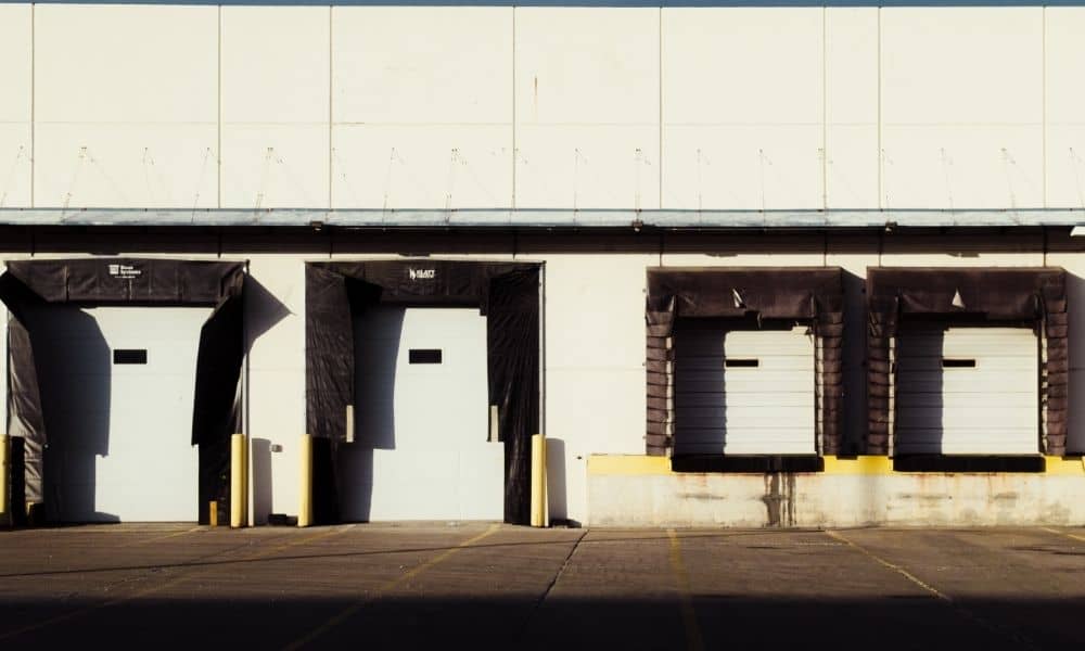 Alta survey industrial loading dock access | ALTA Land Survey Wide view of an industrial loading dock with multiple bay doors, paved access areas, and truck loading spaces, illustrating property access considerations associated with an ALTA survey